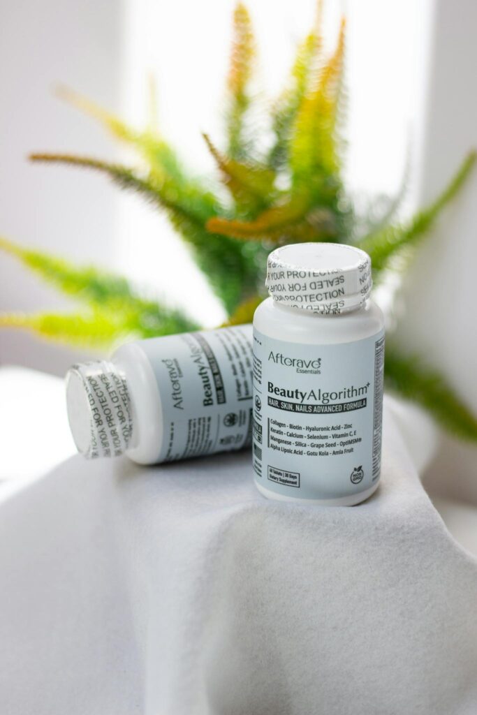 Close-up of Afterave Beauty Algorithm supplements with a fern backdrop, highlighting skincare and wellness.